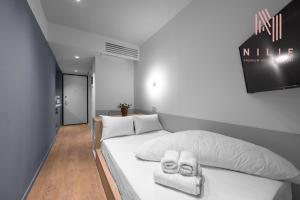 1 dormitorio con 1 cama blanca y 2 toallas en V19, Nilie Hospitality MGMT, en Tesalónica