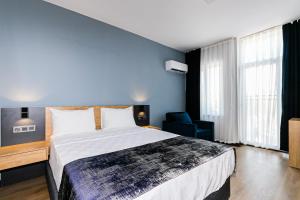 1 dormitorio con 1 cama grande y pared azul en Lara World Hotel, en Antalya