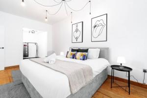 Newtown Loft Apartment - Smart TV- WIFI - Parking 3NT في برمنغهام: غرفة نوم بيضاء بسرير كبير وثريا