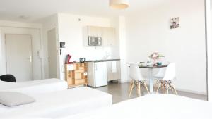 Dieses weiße Apartment verfügt über eine Küche sowie einen Tisch und Stühle. in der Unterkunft Zenao Appart'Hotel in Yzeure