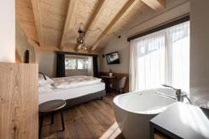 a bedroom with a tub and a bed and a sink at Garnì La Violetta in Soraga