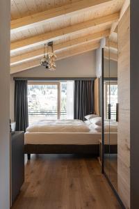 a large bed in a room with a large window at Garnì La Violetta in Soraga