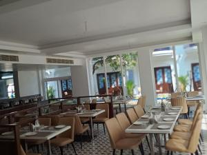 a dining room with tables and chairs and windows at Le MIAMI RESORT in Pondicherry