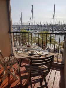 een tafel en stoelen op een balkon met uitzicht op een haven bij T2 sur le port avec parking in Gruissan