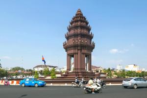 Julieka’s Guesthouse في بنوم بنه: برج الساعة مع وجود دراجات نارية أمام المبنى