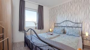 ein Schlafzimmer mit einem Bett mit blauen Kissen und einem Fenster in der Unterkunft Bungalow "Wiesenblick" in Trassenheide