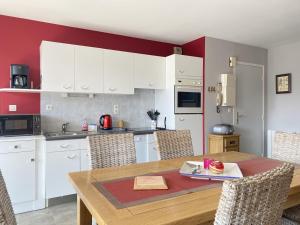 een keuken met witte kasten en een houten tafel met stoelen bij 522 - A Erquy dans une résidence calme à 200m de la Plage in Erquy