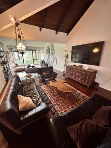 a living room with a leather couch and a flat screen tv at The White Horse in Cameron Highlands