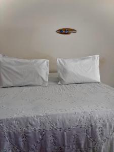 a bed with white sheets and pillows on it at La Pousada in Maceió