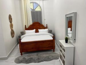 a bedroom with a wooden bed and a mirror at Nashu House Stone Town in Ngambo