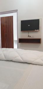 a bed with a flat screen tv on a wall at Modernio Guest House Noida Extension in Greater Noida