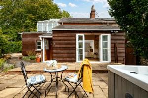 a patio with a table and chairs and a house at Snowdrop - Connect to the Nature in the Hot Tub in Blandford Forum