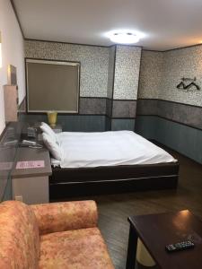 a hotel room with a bed and a chair at ビジネスインＮＡＧＡＳＨＩＭＡ in Hakuro