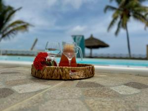 a basket of wine glasses and flowers on a table by a pool at Villa Riacho Doce in Maceió