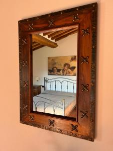 uno specchio a parete con un letto. di LOCANDA PODERE LE VIGNE a Radda in Chianti