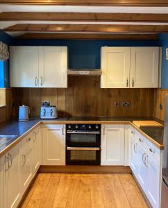 a kitchen with white cabinets and a stove at Charming Farm based cottage with hot tub and sauna in Newton