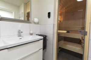ein Bad mit einem Waschbecken und einer Dusche in der Unterkunft Ferienwohnung Meerglück mit Balkon und Sauna - 300 m vom Strand entfernt in Kellenhusen