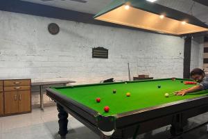 a man is playing pool on a pool table at The Siyona Resort in Rāmnagar