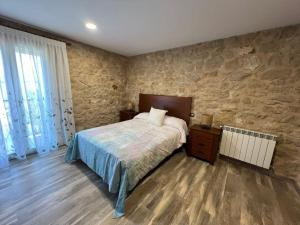 a bedroom with a bed and a stone wall at Casa Rural La Atalaya in Montarrón