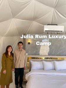 a man and a woman standing next to a bed at Julia Rum Luxury Camp in Wadi Rum