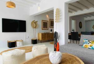 a living room with a table and chairs and a tv at Villa Elia Breeze Mykonos in Mikonos