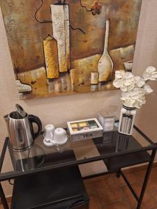 una mesa de cristal con cafetera y flores. en GIRASOLE Wellness e Relax, en Fossano