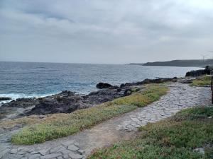 un camino de piedra junto a un cuerpo de agua en PlayaLasRicas en Las Eras