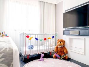 a teddy bear sitting in a crib in a bedroom at Mercure Sao Paulo Ibirapuera Privilege in Sao Paulo