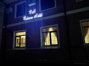 a brick building with a lit up sign on it at Gulnora HOTEL in Uzbankinty