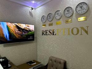 una habitación con relojes en la pared con las palabras retenidas en Gulnora HOTEL en Uzbankinty