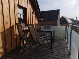 a balcony with a table and chairs on a deck at Ferienwohnung am Kalten Bach in Dürrröhrsdorf +2 photos