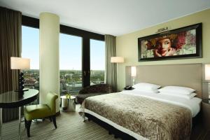 デュッセルドルフにあるHyatt Regency Dusseldorfのベッド、デスク、テレビが備わるホテルルームです。