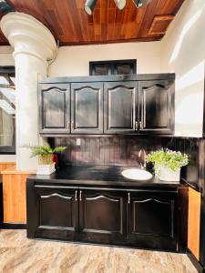 a kitchen with black cabinets and a sink at Homestay Thác Liên Khương in Ðưc Trọng