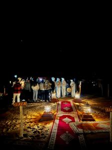 een groep mensen die rond een tafel met kaarsen staan bij Dream luxury camp in Merzouga +77 foto's