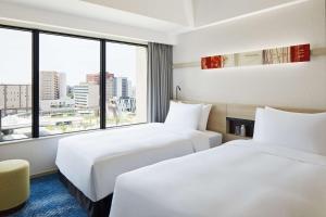 two beds in a hotel room with a large window at Hyatt House Kanazawa in Kanazawa +82 photos