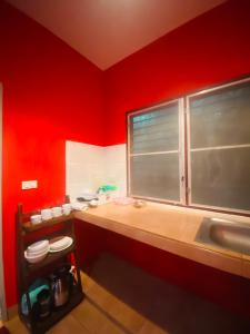 a red kitchen with a sink and a window at Rose bungalow at Ya Nui beach in Nai Harn Beach