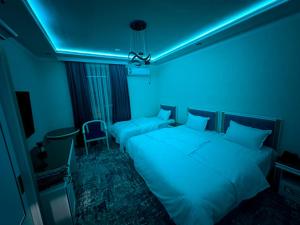 a dark room with two beds and a blue light at Gulnora HOTEL in Uzbankinty