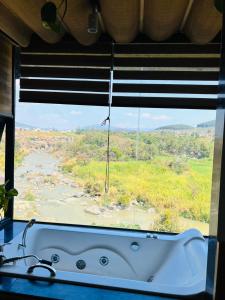 uma banheira numa janela com vista para um rio em Homestay Thác Liên Khương em Ðưc Trọng