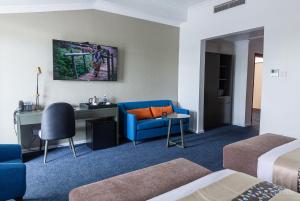 a hotel room with a blue couch and a desk at Gloria Inn Hotel - Ndola in Ndola