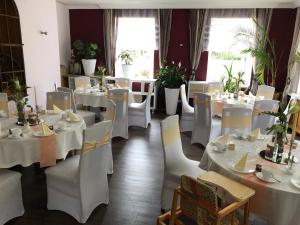 a dining room with white tables and white chairs at Hotel Weinhaus Eberitzsch GmbH in Bad Blankenburg