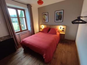 Schlafzimmer mit einem Bett mit roter Bettwäsche und einem Fenster in der Unterkunft Logement Spacieux in Fraize