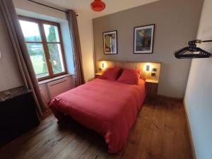 Un dormitorio con una cama con sábanas rojas y una ventana. en Logement Spacieux, en Fraize