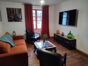 Una sala de estar con un sofá y un televisor. en Logement Spacieux, en Fraize