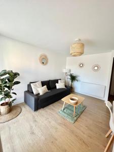 uma sala de estar com um sofá preto e uma mesa em Appartement Cosy - Cap d'Agde proche plage et port - Parking em Cap d'Agde