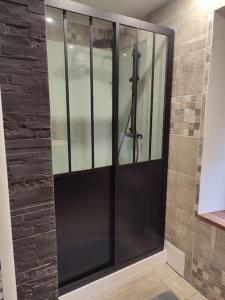 eine Duschkabine mit Glastüren im Bad in der Unterkunft Logement Spacieux in Fraize