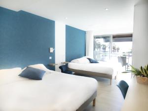 1 dormitorio con 2 camas y pared azul en Tiercé Hotel, en Cagnes-sur-Mer