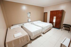 Habitación con 2 camas y una silla. en SERRA AZUL PLAZA HOTEL, en Barra do Garças