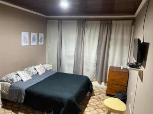 a bedroom with a bed and a flat screen tv at Guembe al Rio Hostel in Puerto Iguazú
