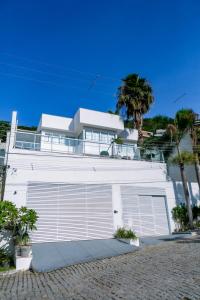a white building with two garage doors and a palm tree at Mansão & Loft Exclusivo Vista Mar in Niterói