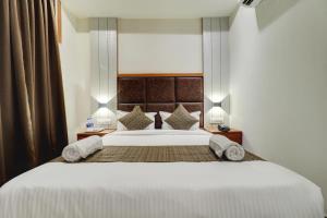 a bedroom with a large white bed with two pillows at Hotel Sion Fort in Mumbai